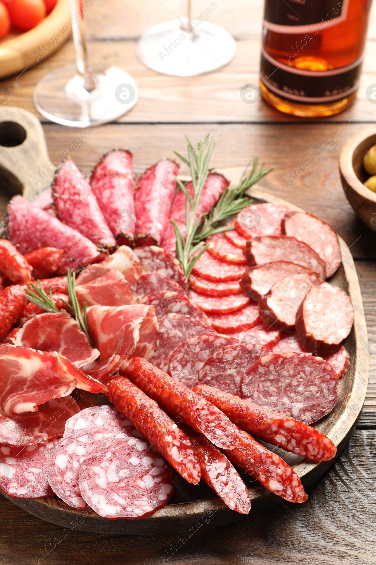 Photo of Different smoked sausages slices served on wooden table closeup