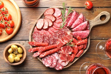 Photo of Different smoked sausages slices served on wooden table, flat lay