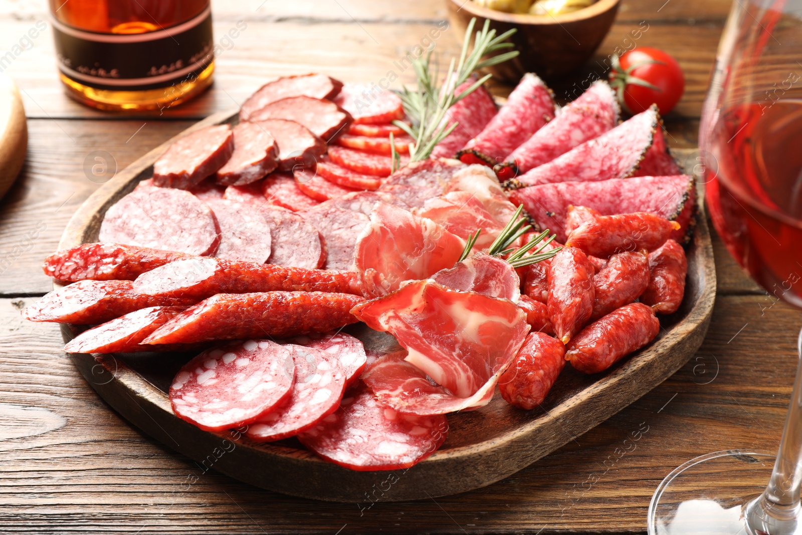 Photo of Different smoked sausages slices served on wooden table closeup