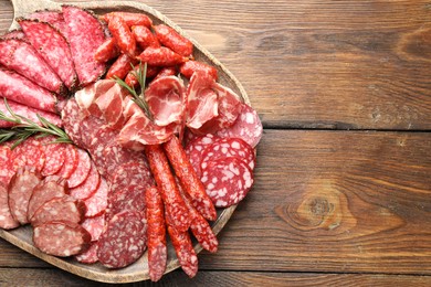 Photo of Different smoked sausages slices served on wooden table, top view. Space for text