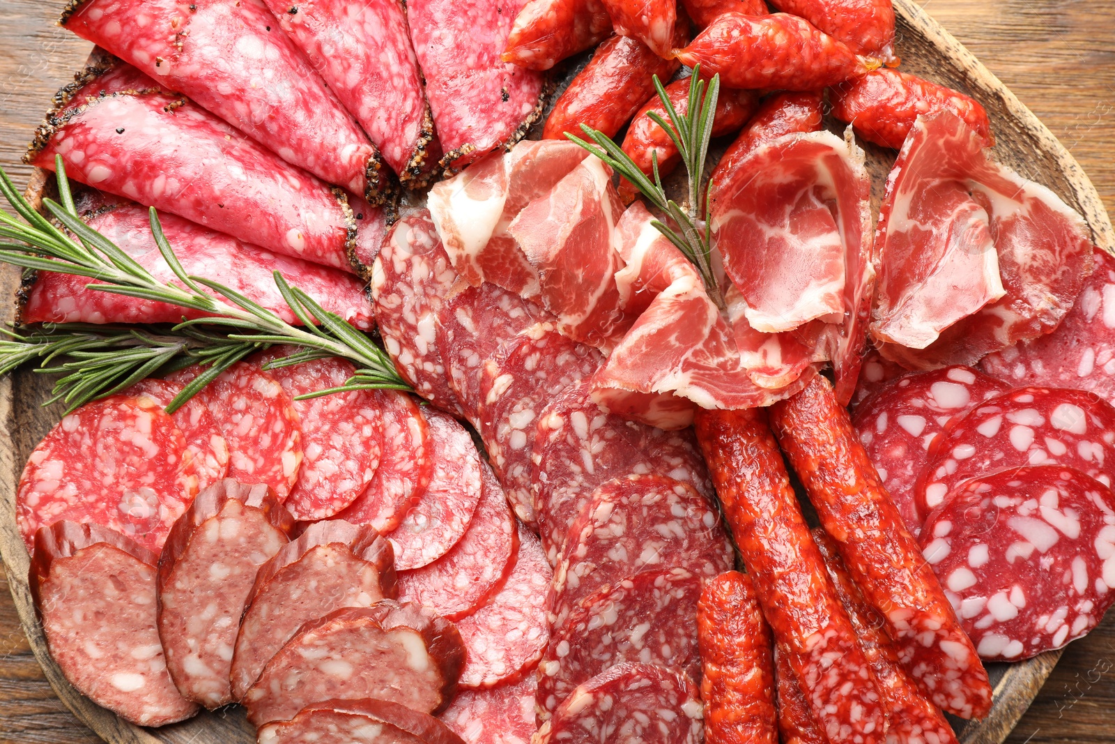 Photo of Different smoked sausages slices served on wooden table closeup