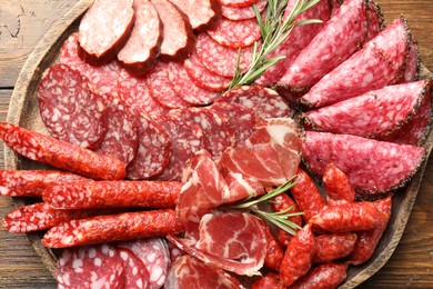 Photo of Different smoked sausages slices served on wooden table, top view