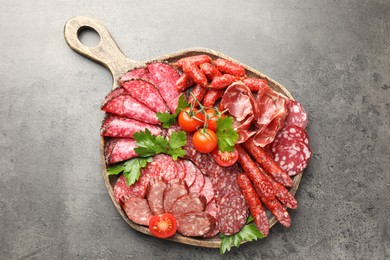 Photo of Different smoked sausages slices served on grey table, top view