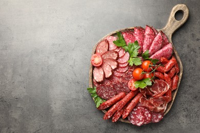 Photo of Different smoked sausages slices served on grey table, top view. Space for text