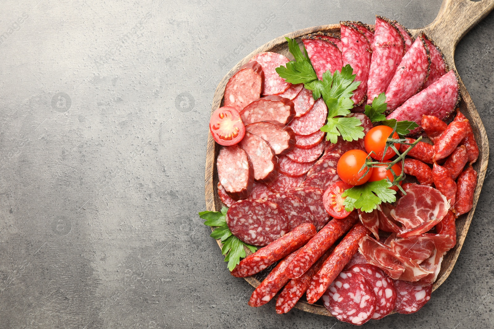 Photo of Different smoked sausages slices served on grey table, top view. Space for text