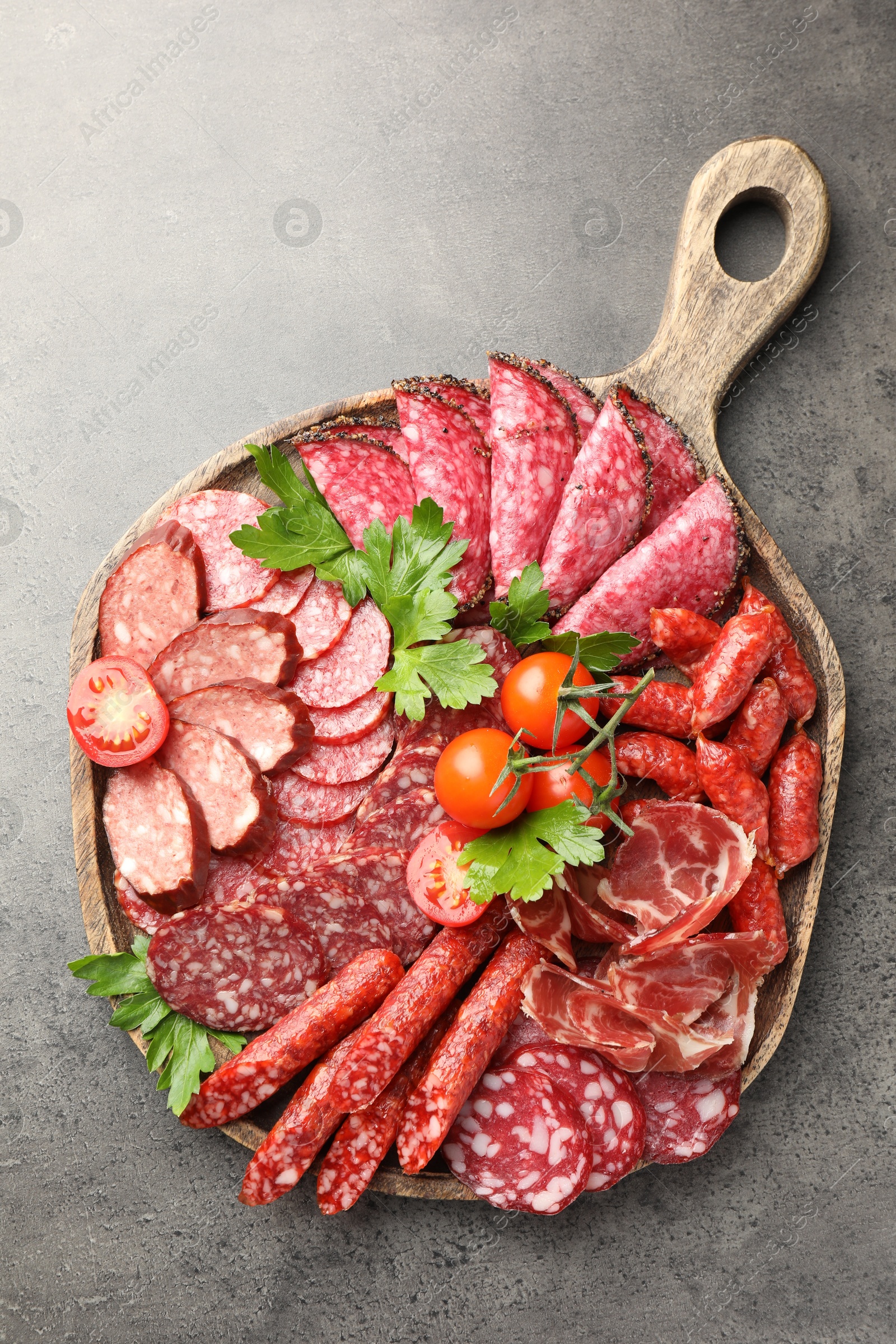 Photo of Different smoked sausages slices served on grey table, top view