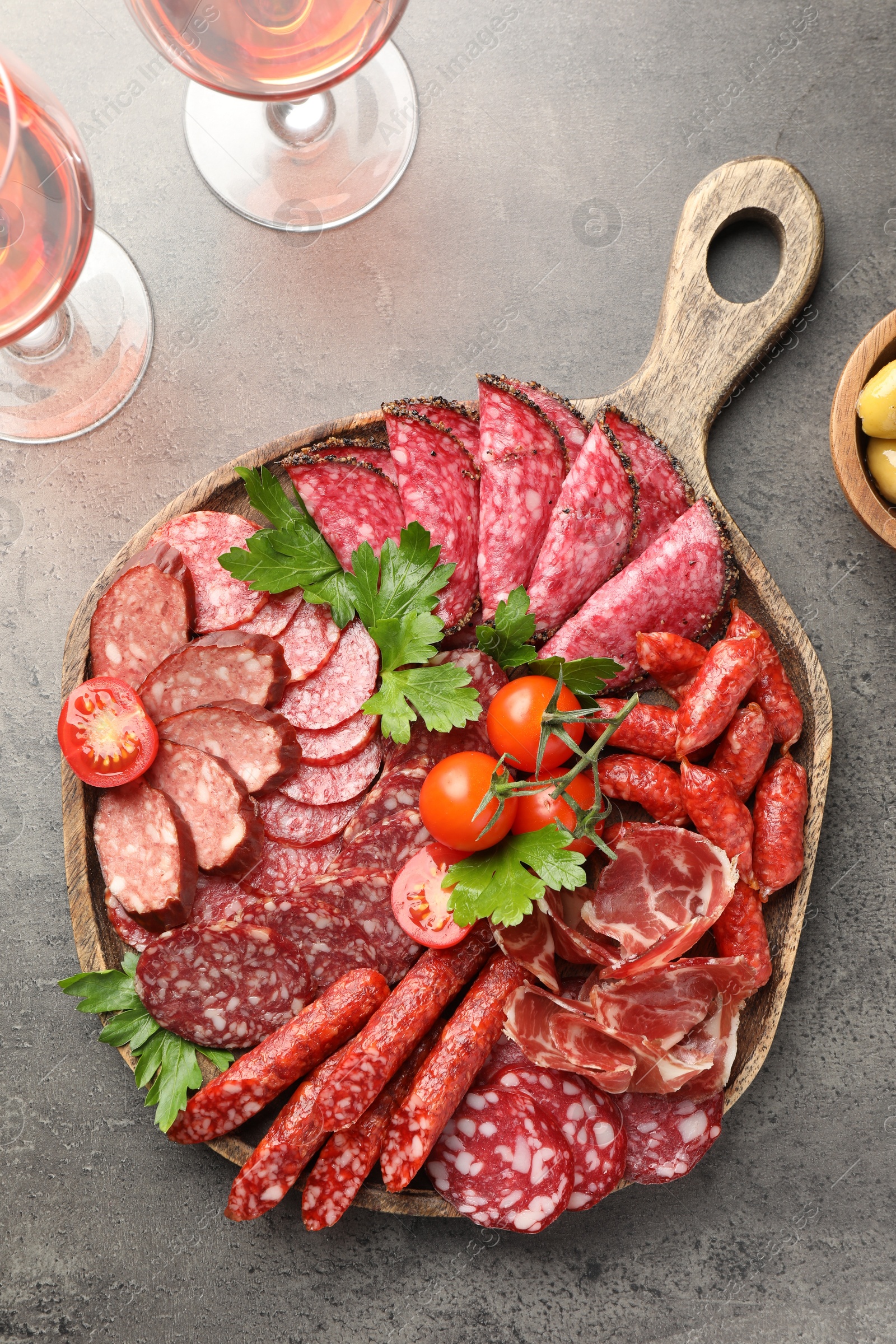 Photo of Different smoked sausages slices served on grey table, flat lay