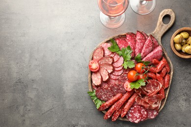 Photo of Different smoked sausages slices served on grey table, flat lay. Space for text