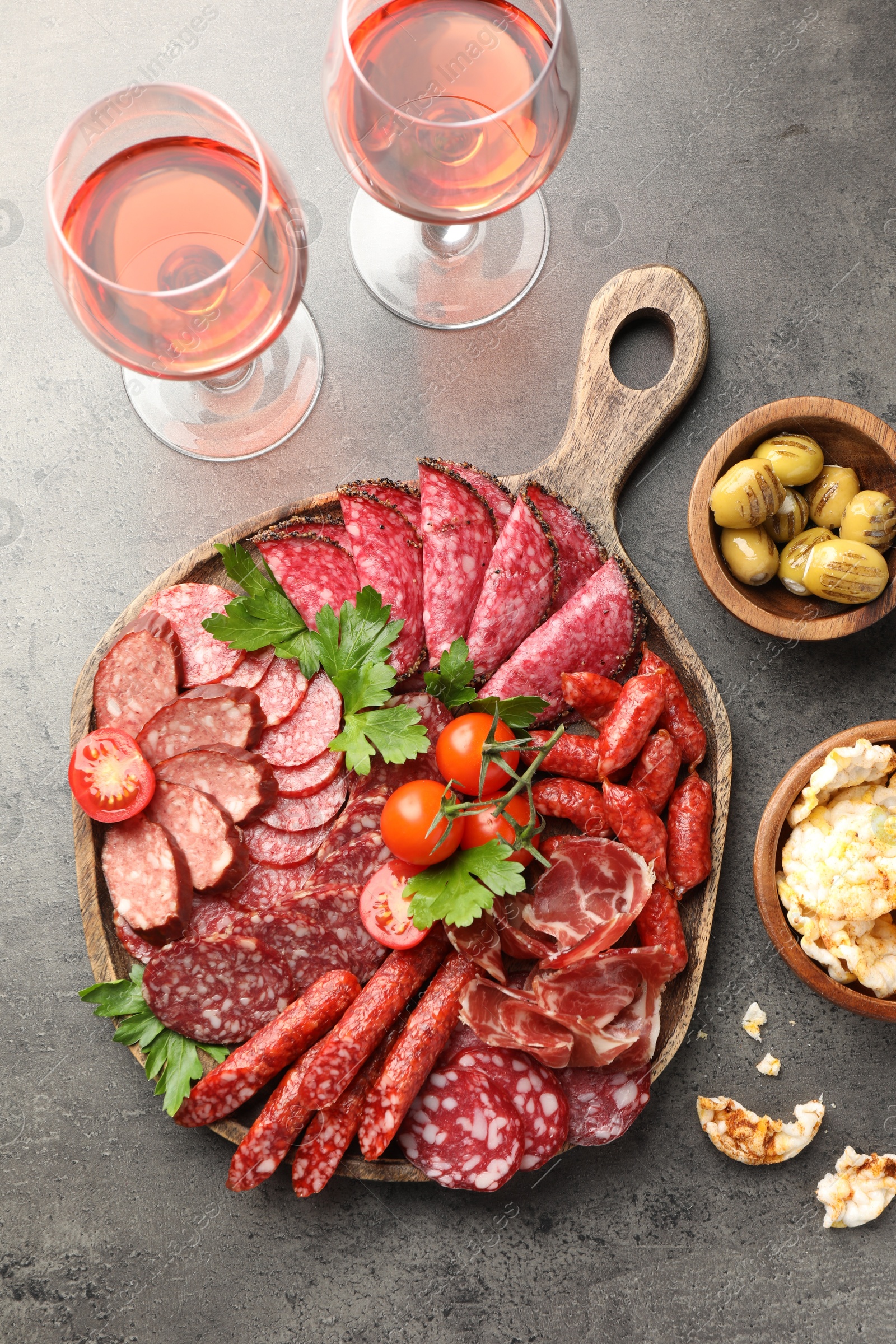 Photo of Different smoked sausages slices served on grey table, flat lay