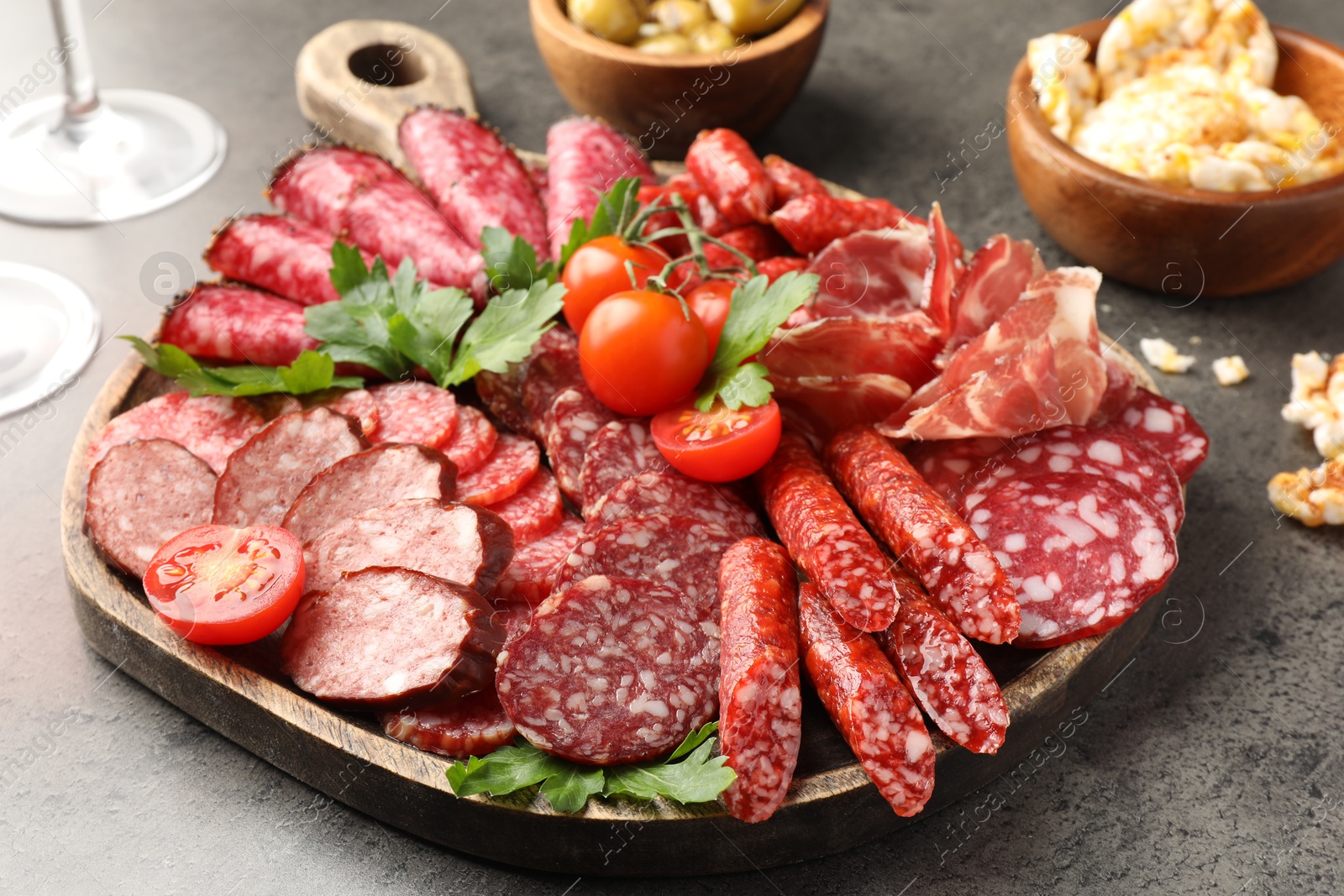 Photo of Different smoked sausages slices served on grey table, closeup