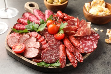 Photo of Different smoked sausages slices served on grey table, closeup