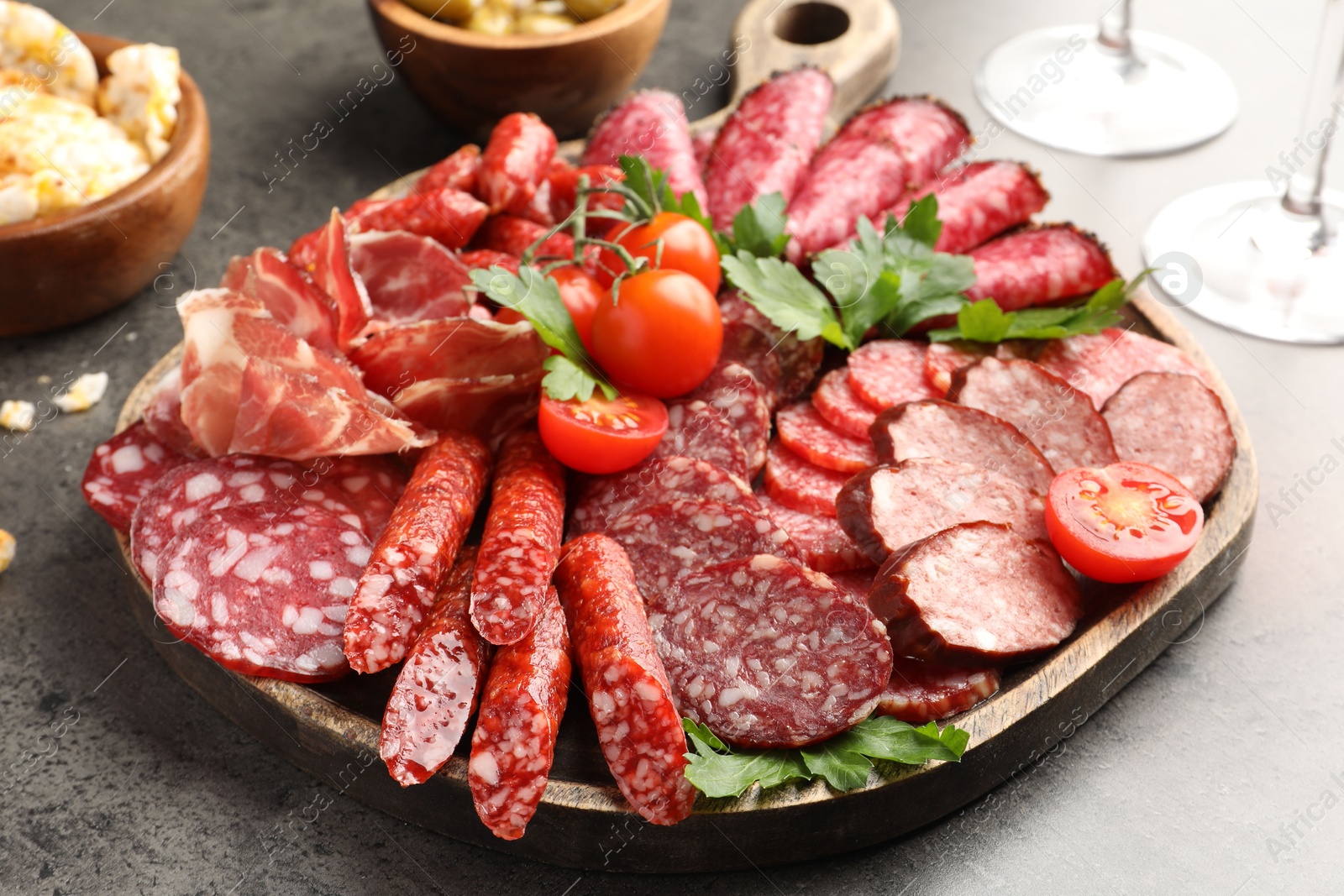 Photo of Different smoked sausages slices served on grey table, closeup