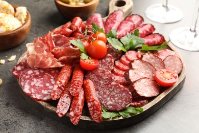 Photo of Different smoked sausages slices served on grey table, closeup