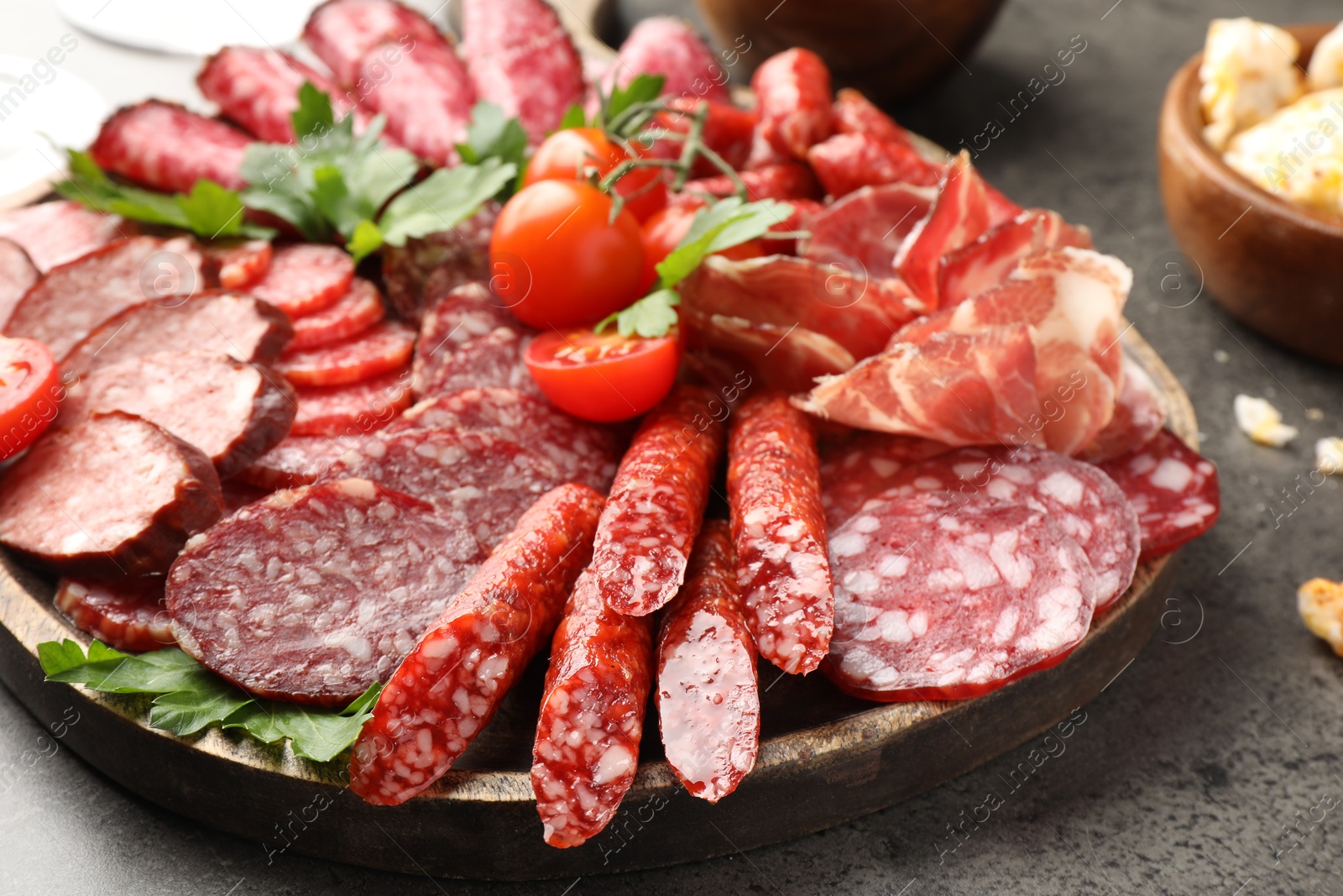 Photo of Different smoked sausages slices served on grey table, closeup