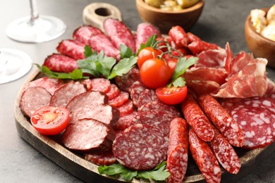 Photo of Different smoked sausages slices served on grey table, closeup