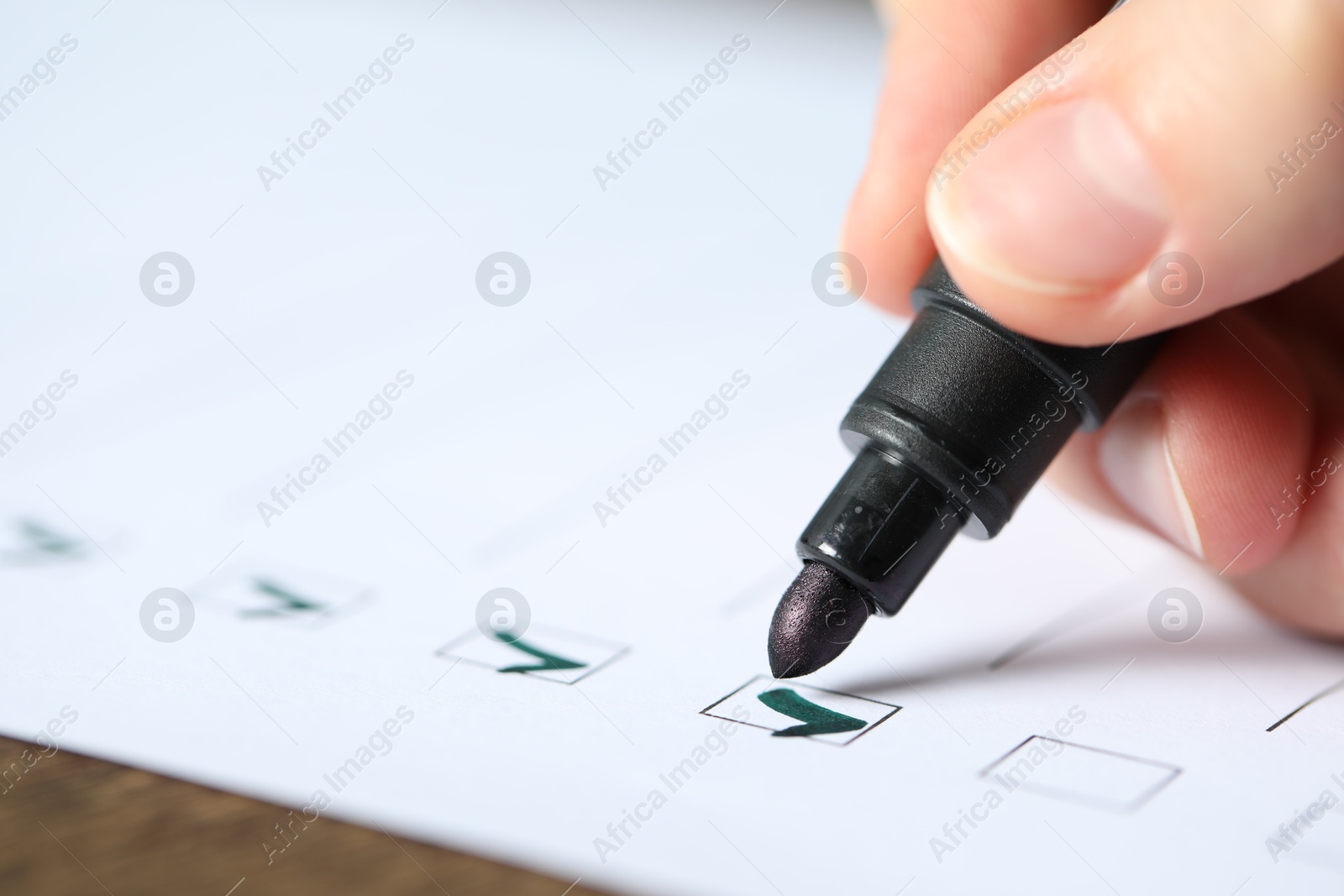 Photo of Woman checking box of paper form at table, closeup