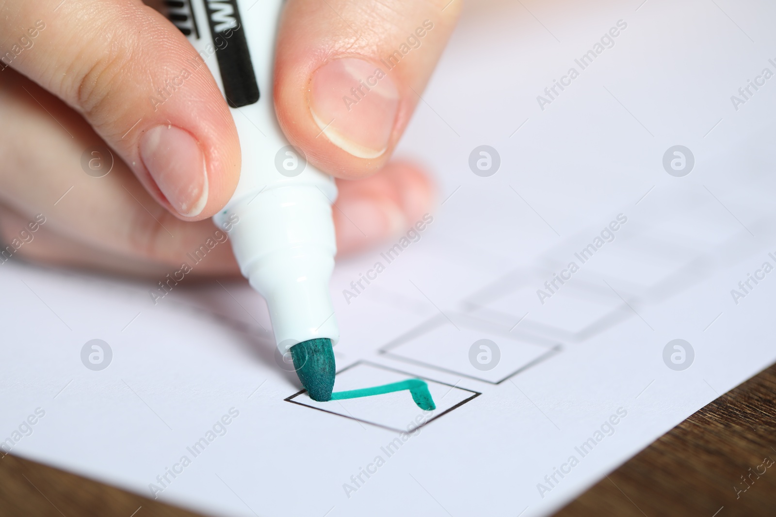 Photo of Woman checking box of paper form at wooden table, closeup