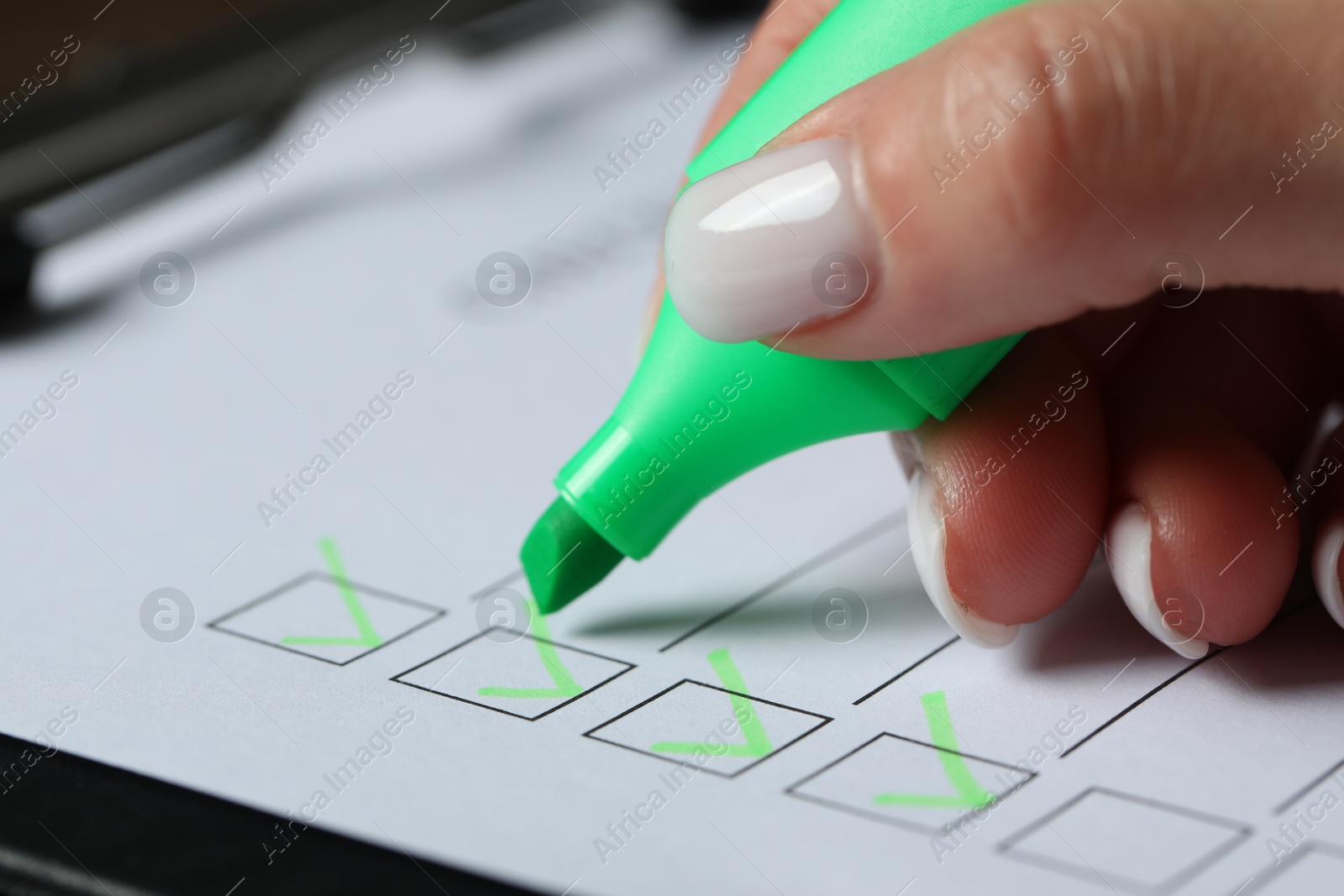 Photo of Woman checking box of paper form at table, closeup