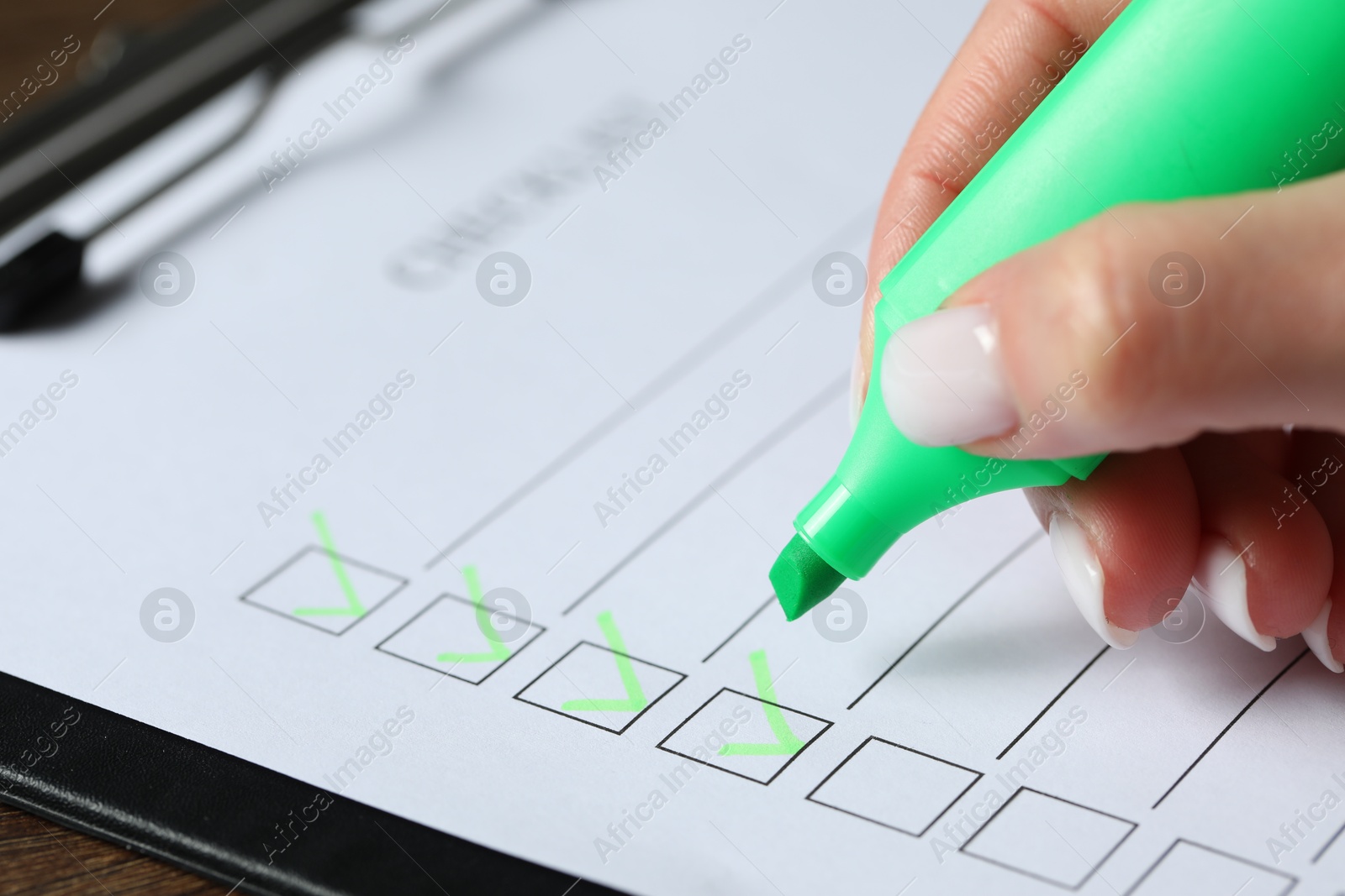 Photo of Woman checking box of paper form at table, closeup