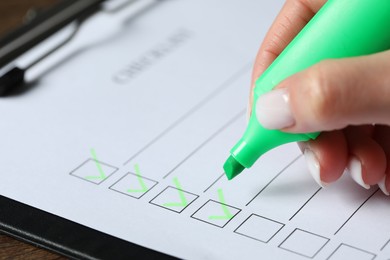 Photo of Woman checking box of paper form at table, closeup