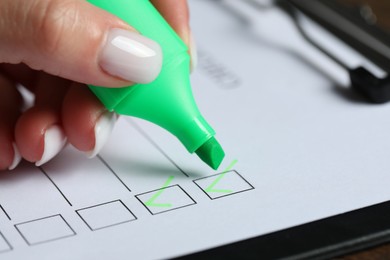 Photo of Woman checking box of paper form at table, closeup