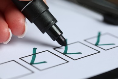 Photo of Woman checking box of paper form at table, closeup