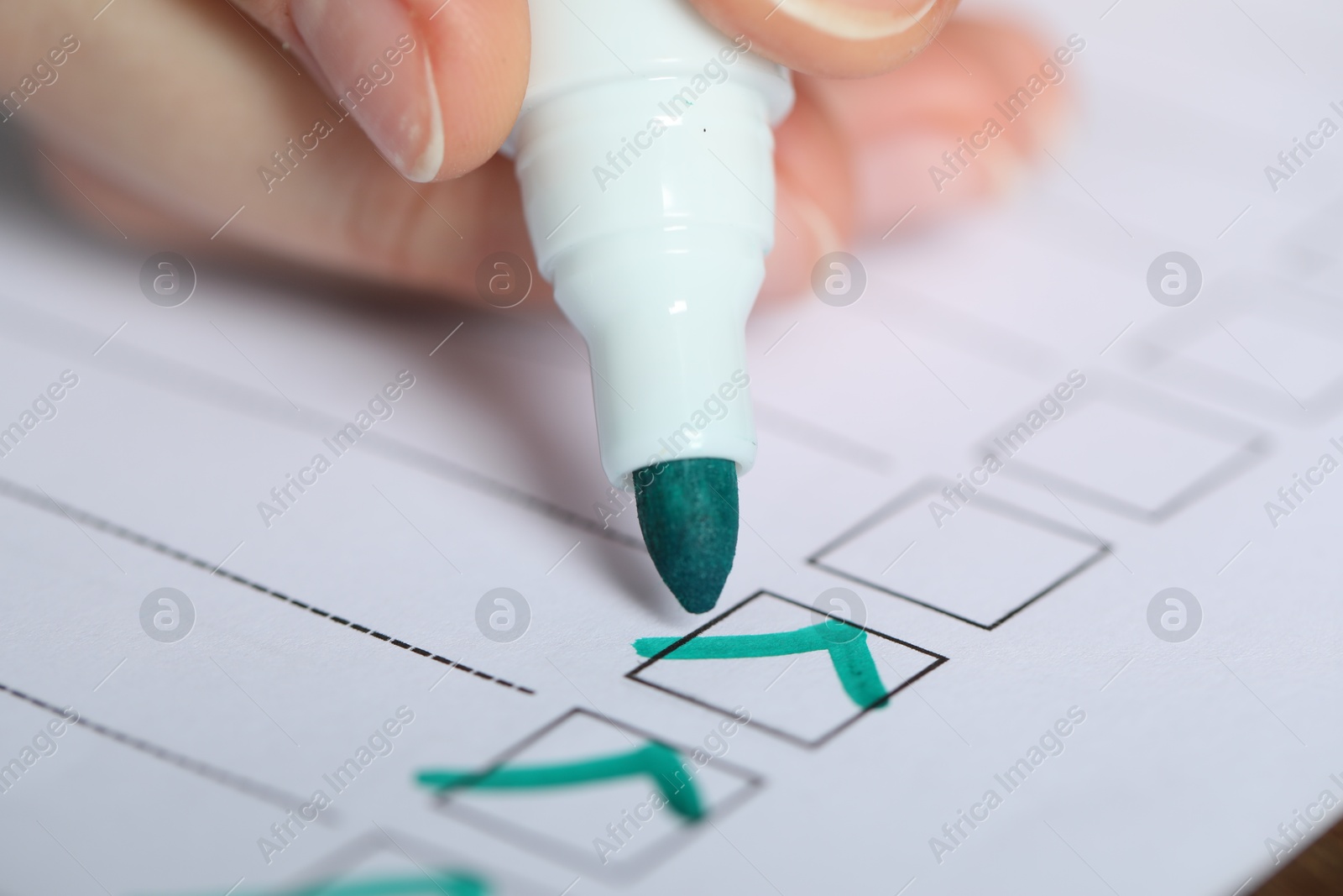 Photo of Woman checking box of paper form at table, closeup