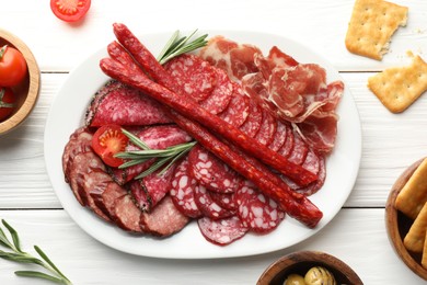 Photo of Different smoked sausages slices served on white wooden table, flat lay