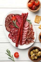 Photo of Different smoked sausages slices served on white wooden table, flat lay