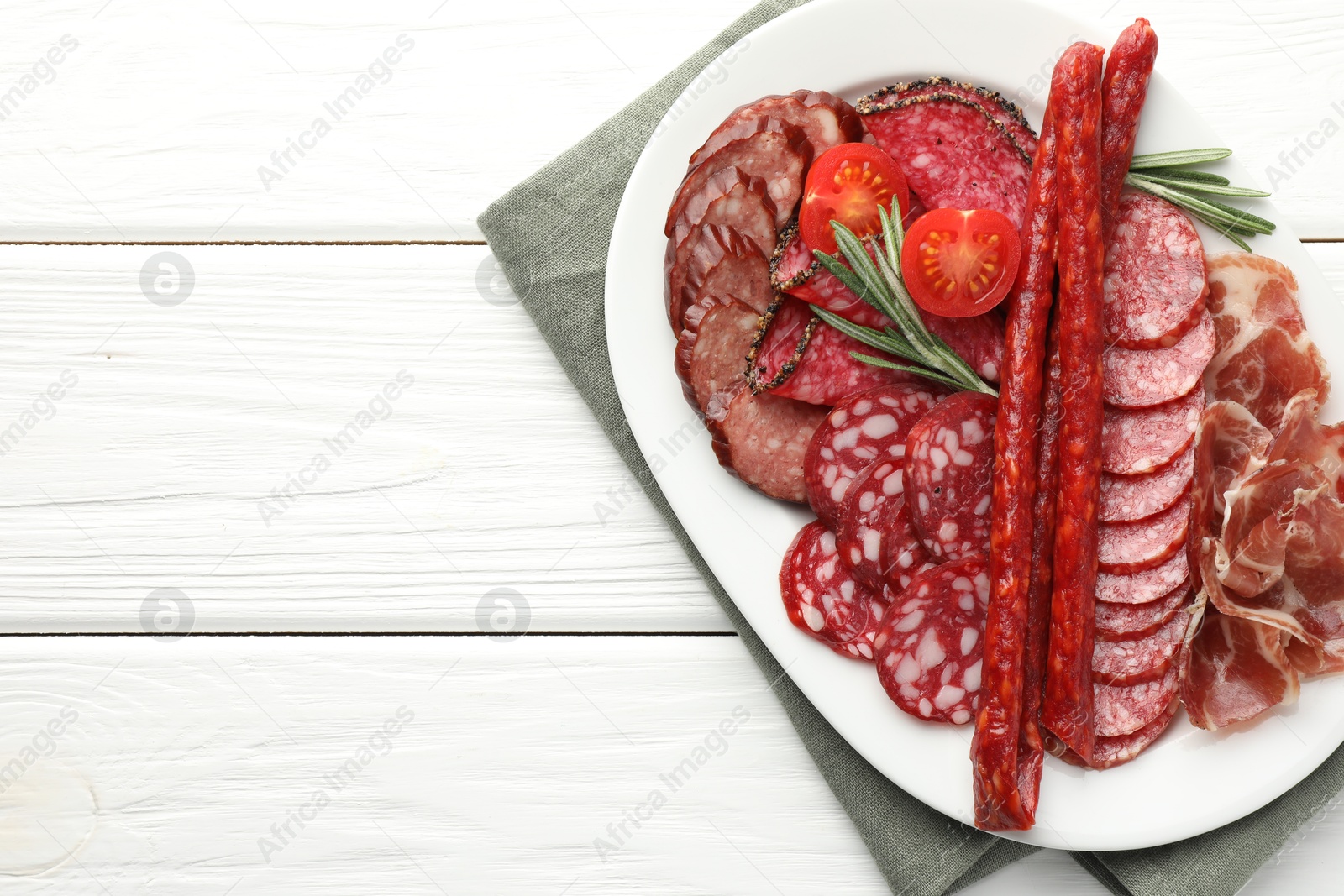 Photo of Different smoked sausages slices served on white wooden table, top view. Space for text