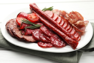 Photo of Different smoked sausages slices served on white wooden table, closeup