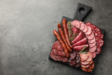 Photo of Different smoked sausages slices served on grey table, top view. Space for text