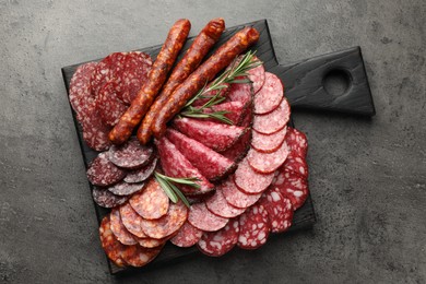 Photo of Different smoked sausages slices served on grey table, top view