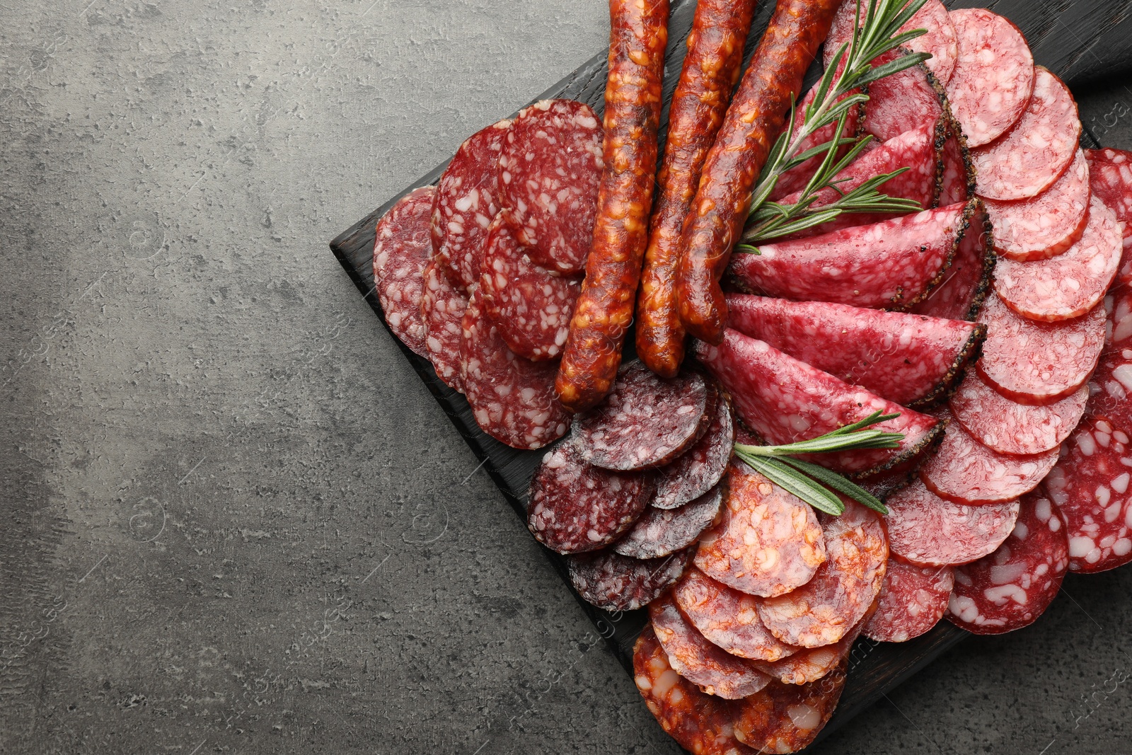 Photo of Different smoked sausages slices served on grey table, top view. Space for text