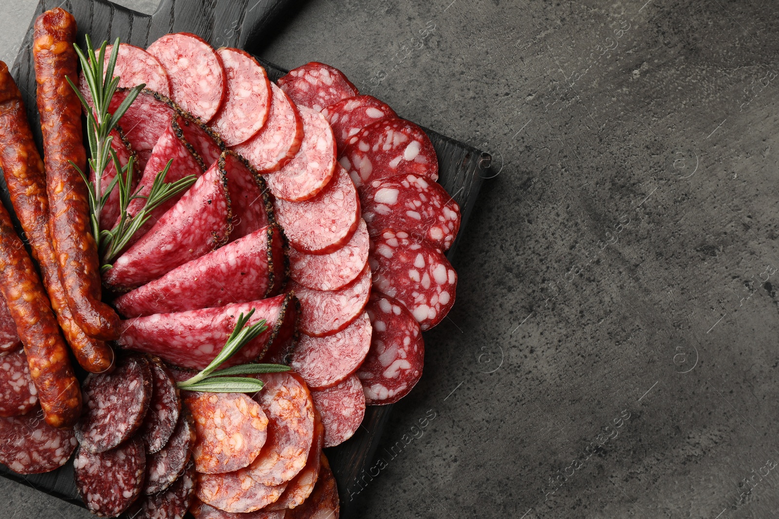 Photo of Different smoked sausages slices served on grey table, top view. Space for text