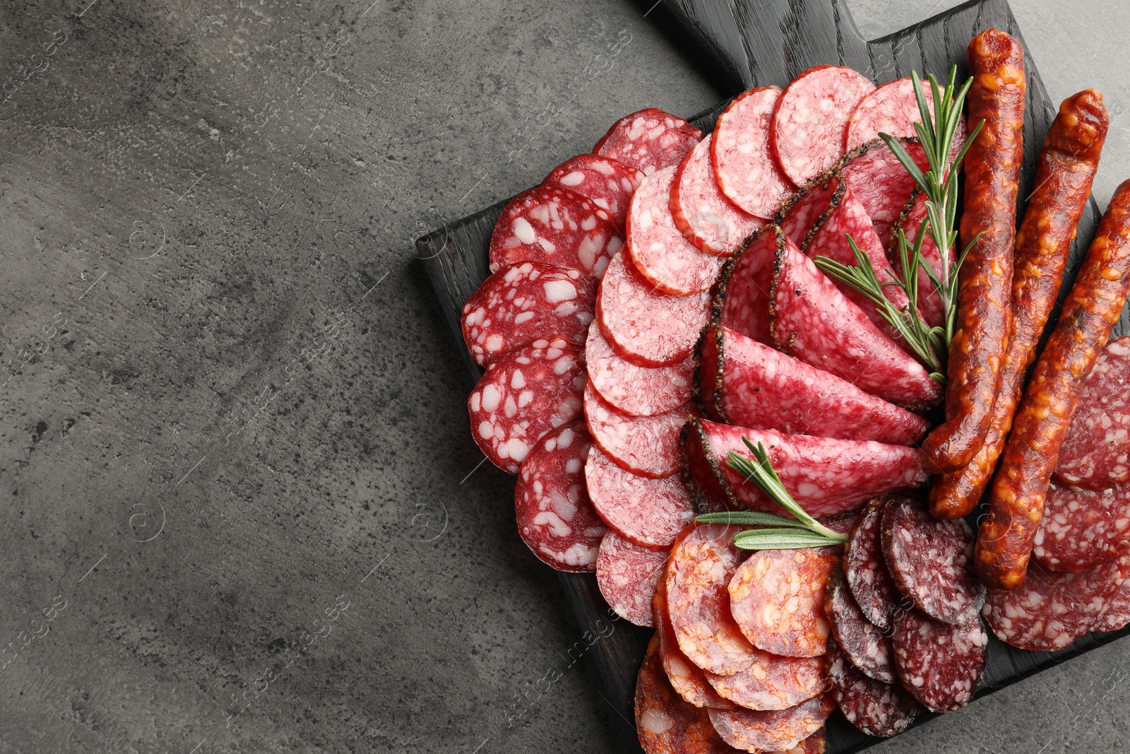 Photo of Different smoked sausages slices served on grey table, top view. Space for text