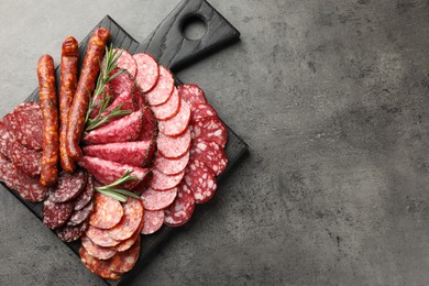 Photo of Different smoked sausages slices served on grey table, top view. Space for text