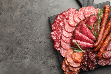 Photo of Different smoked sausages slices served on grey table, top view. Space for text