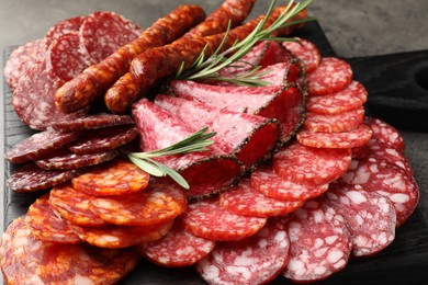 Photo of Different smoked sausages slices served on grey table, closeup