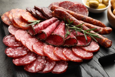 Photo of Different smoked sausages slices served on grey table, closeup