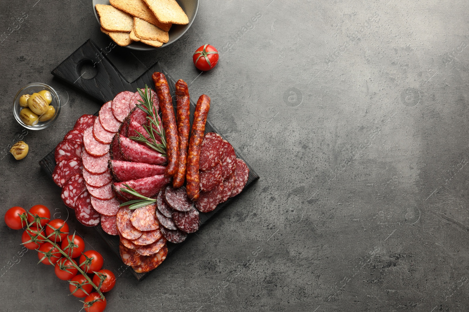 Photo of Different smoked sausages slices served on grey table, flat lay. Space for text