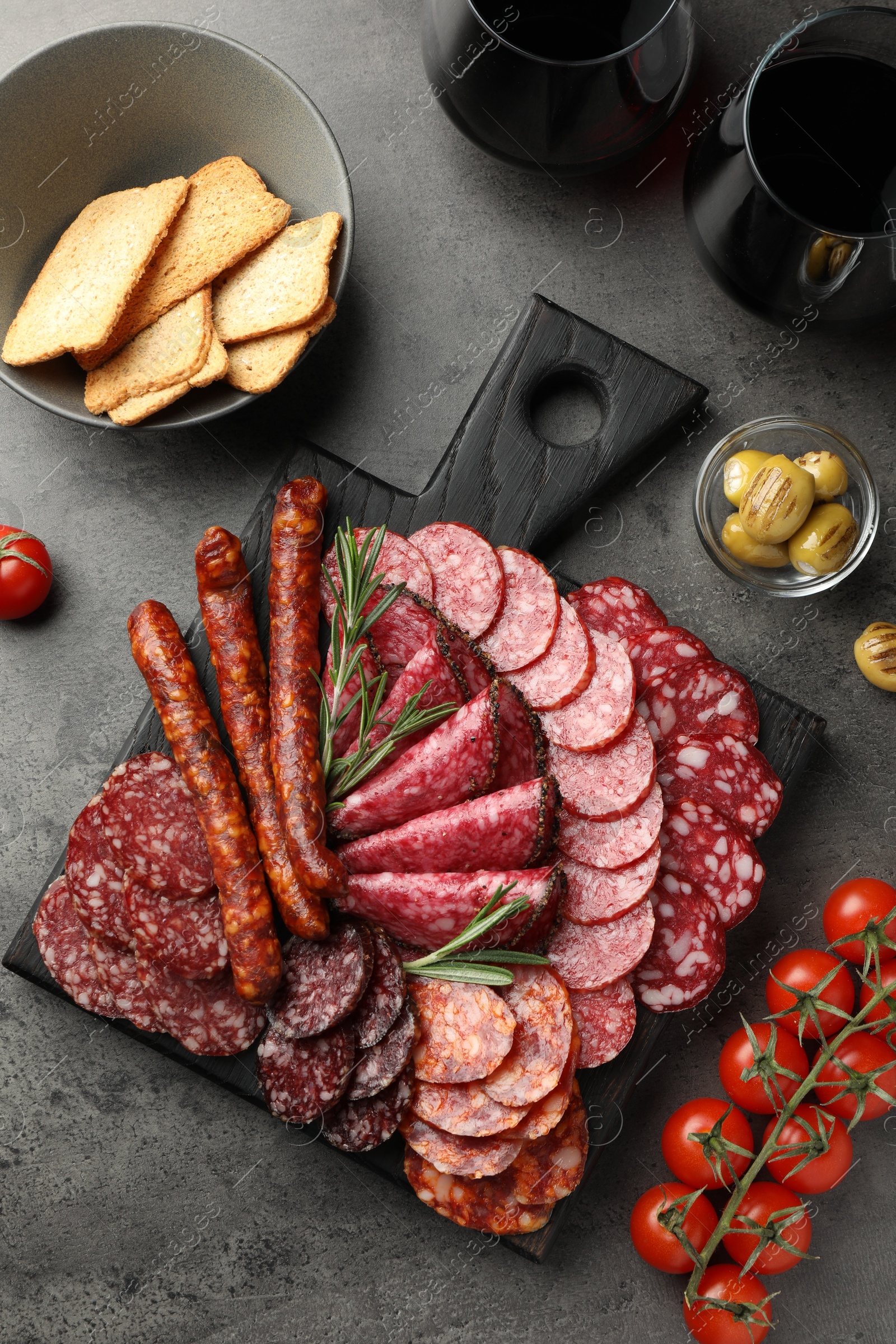 Photo of Different smoked sausages slices served on grey table, flat lay