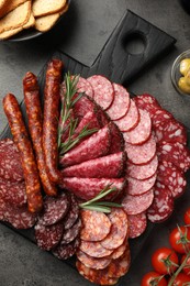 Photo of Different smoked sausages slices served on grey table, flat lay