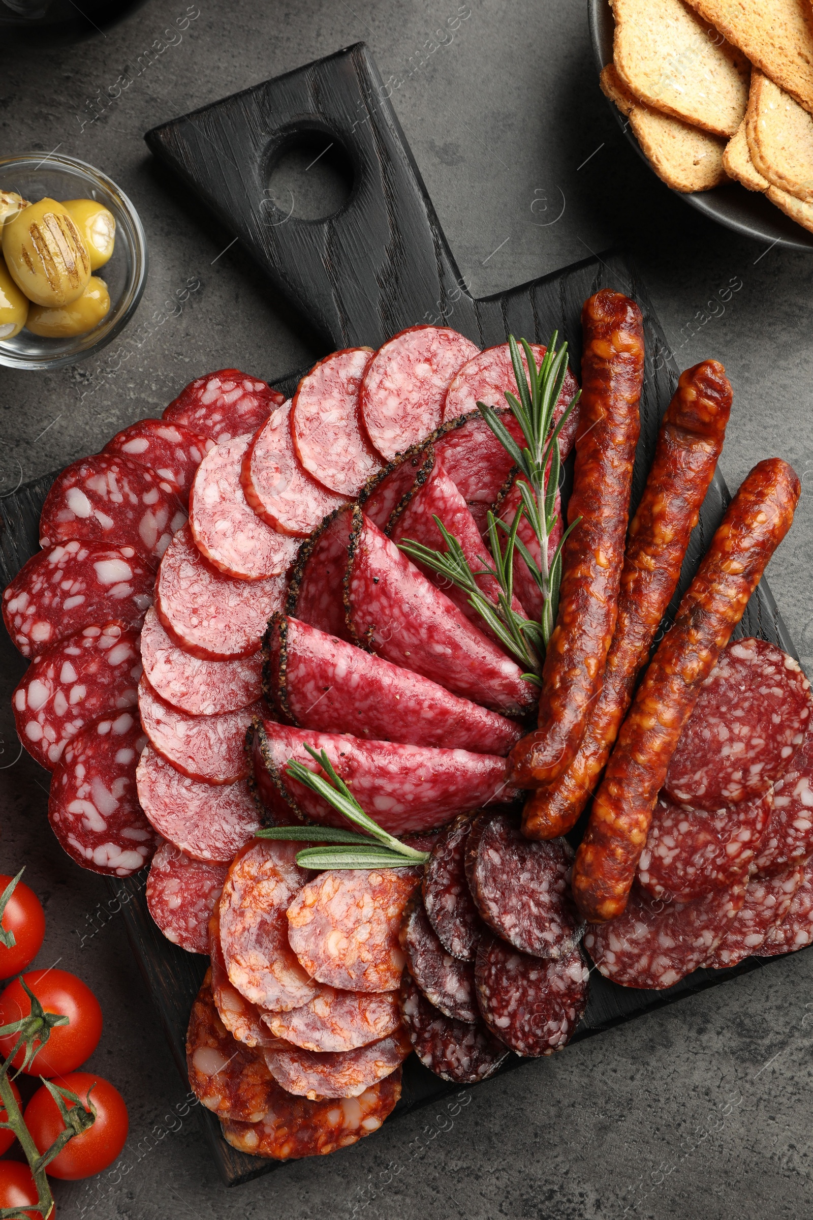 Photo of Different smoked sausages slices served on grey table, flat lay