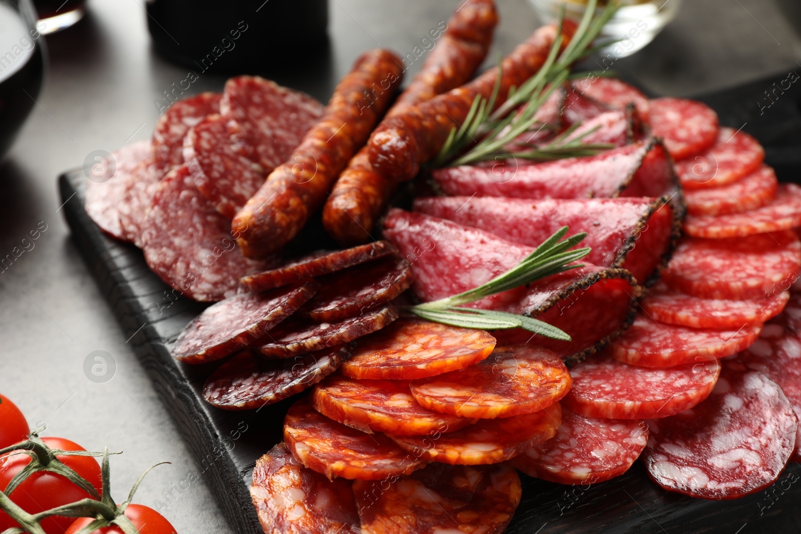 Photo of Different smoked sausages slices served on grey table, closeup