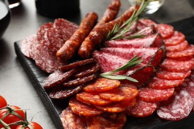 Photo of Different smoked sausages slices served on grey table, closeup