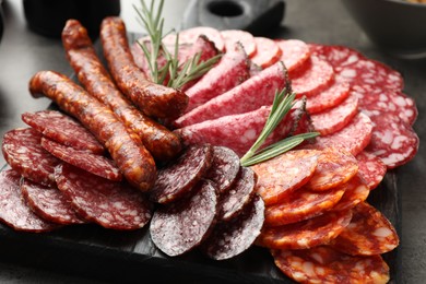 Photo of Different smoked sausages slices served on grey table, closeup