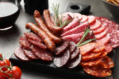 Photo of Different smoked sausages slices served on grey table, closeup