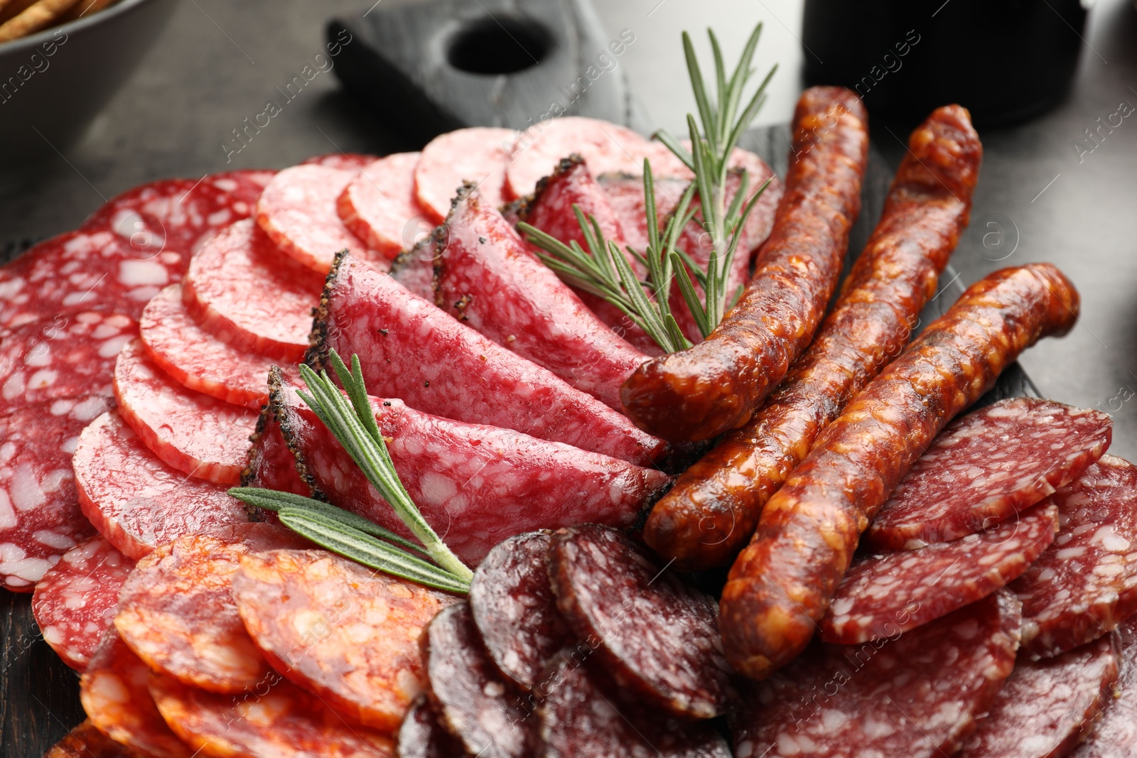 Photo of Different smoked sausages slices served on grey table, closeup