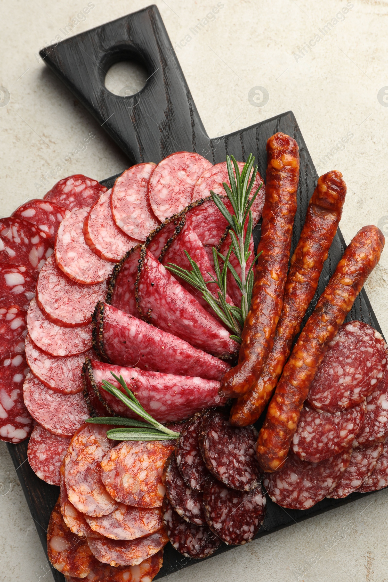 Photo of Different smoked sausages slices served on light table, top view